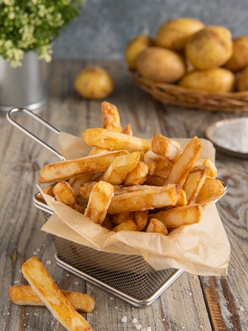 Patatine fritte dorate e croccanti servite in cestino con carta da forno