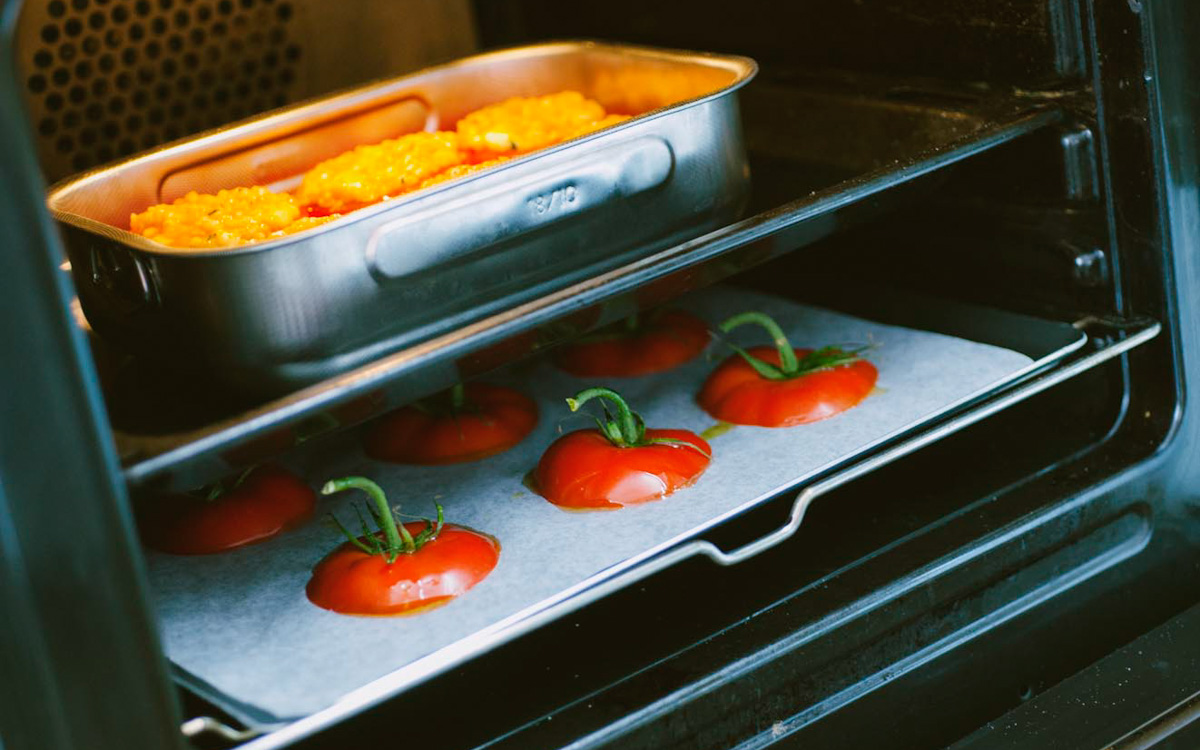 Pomodori interi in cottura in forno, con le calotte disposte sul ripiano inferiore