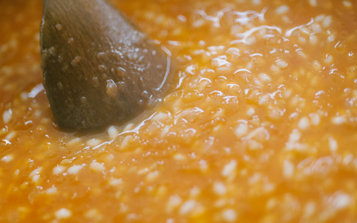 Riso al pomodoro mescolato con un cucchiaio di legno mentre sobbolle denso e cremoso