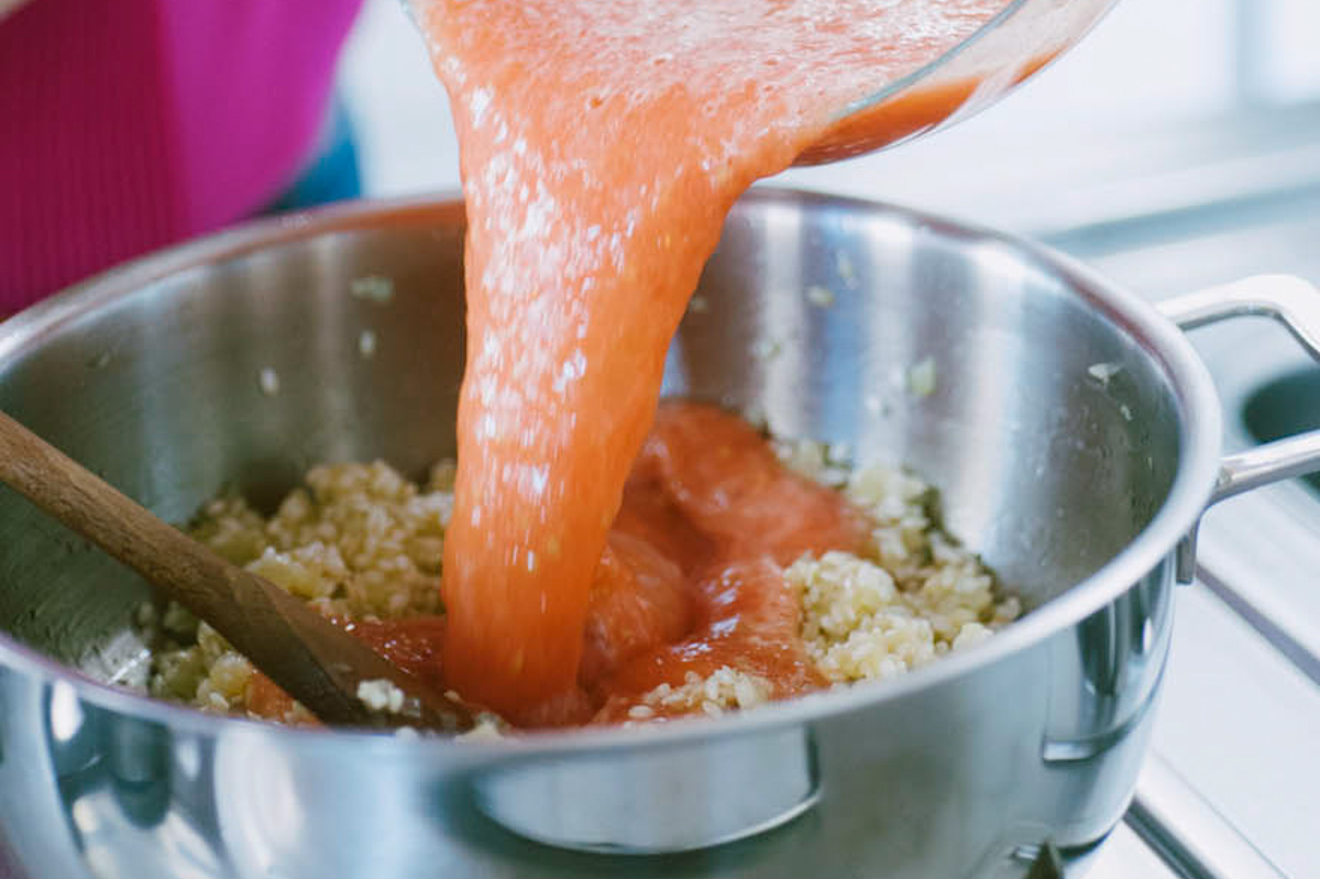 Polpa di pomodoro frullata versata a filo sul soffritto di cipolla in casseruola