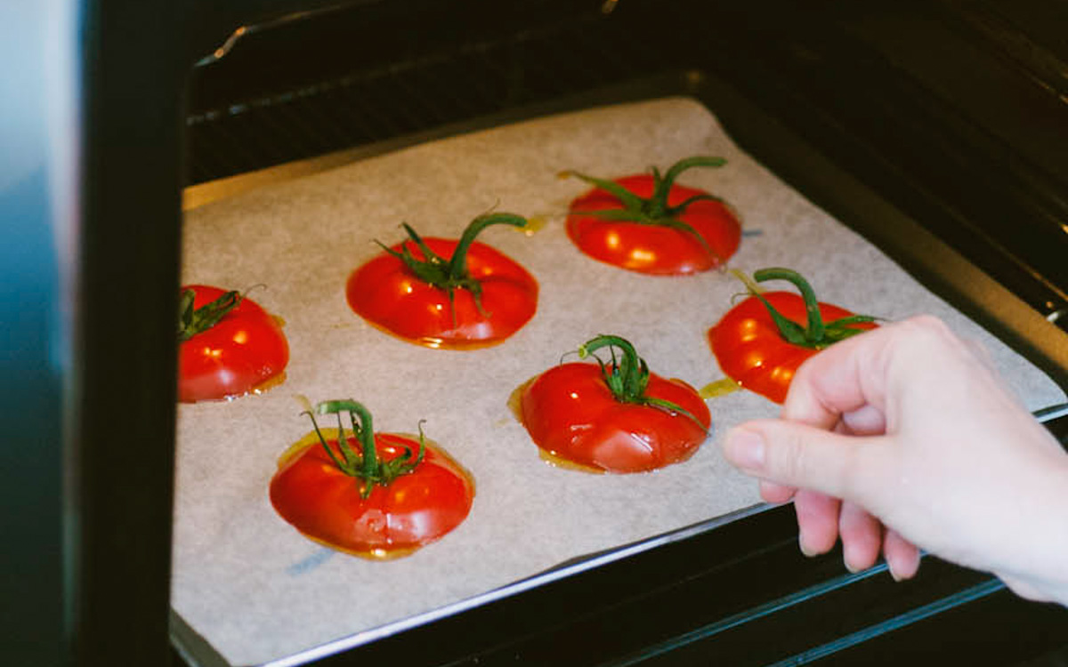 Calotte di pomodoro con picciolo disposte su carta forno, pronte per entrare in forno