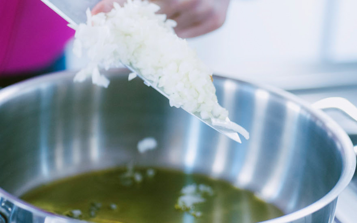 Cipolla tritata finemente versata nell'olio caldo in pentola