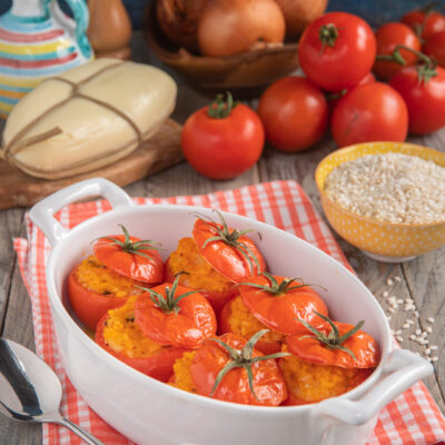 Pomodori ripieni di riso al forno con ripieno dorato e cappette rimesse sui pomodori