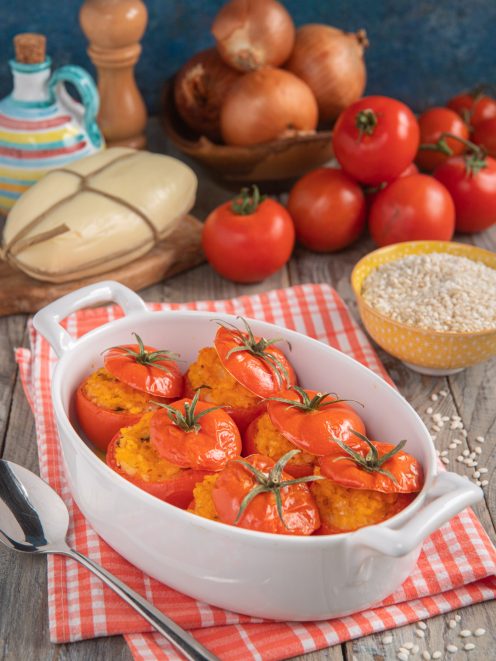 Pomodori ripieni di riso al forno con ripieno dorato e cappette rimesse sui pomodori