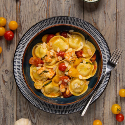 Ravioli agli asparagi con gamberi, pomodorini rossi e gialli e scaglie di mandorle tostate