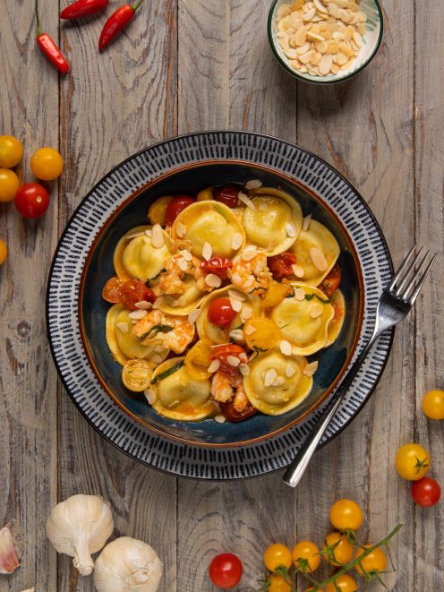 Ravioli agli asparagi con gamberi, pomodorini rossi e gialli e scaglie di mandorle tostate