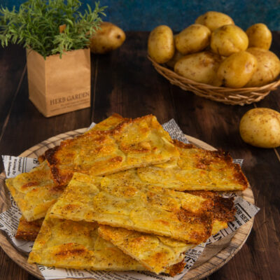 Schiacciata di patate tagliata a pezzi irregolari, dorata e croccante in superficie con spezie