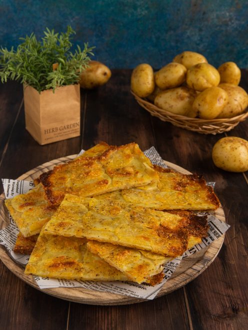 Schiacciata di patate tagliata a pezzi irregolari, dorata e croccante in superficie con spezie