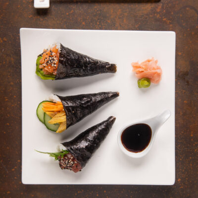 Tre temaki di nori con salmone, verdure e tonno serviti con salsa di soia e zenzero