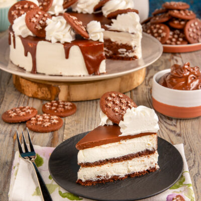 Torta pan di stelle con strati di crema, glassa al cioccolato a colata e biscotti in superficie
