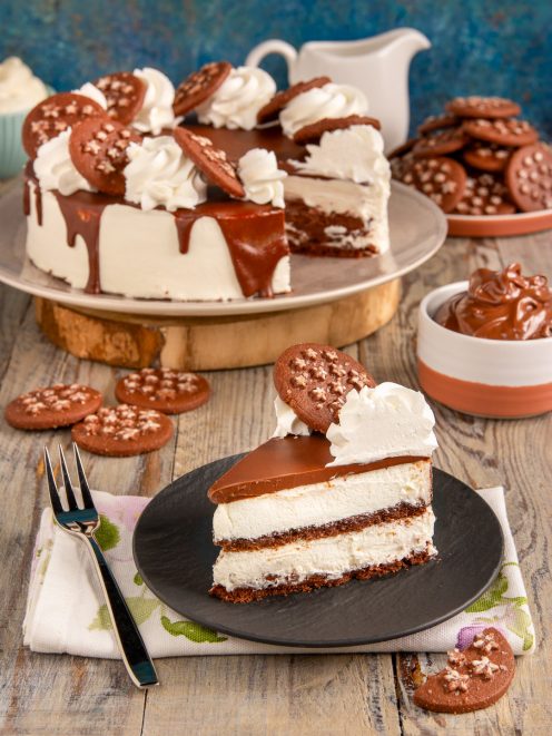 Torta pan di stelle con strati di crema, glassa al cioccolato a colata e biscotti in superficie