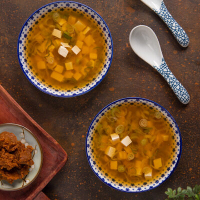 Zuppa di miso con cubetti di tofu e rondelle di cipollotto in brodo ambrato