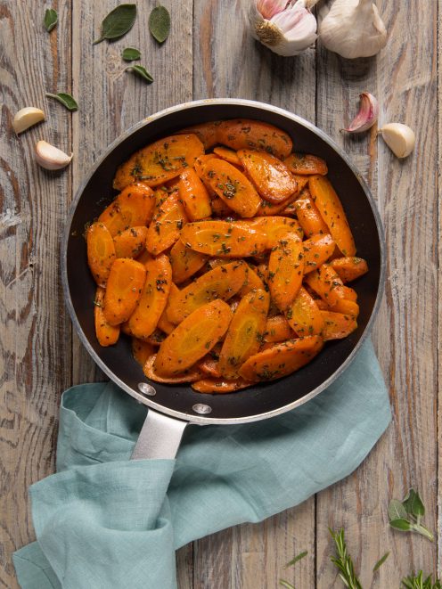 Carote in padella saltate con aglio ed erbe aromatiche tritate, lucide e ben caramellate