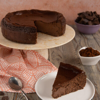 Cheesecake basca al cioccolato con una fetta tagliata e servita su piattino accanto