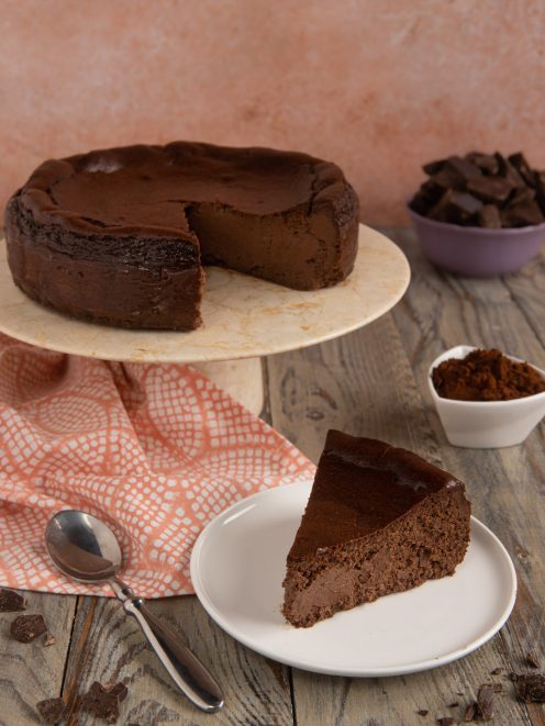 Cheesecake basca al cioccolato con una fetta tagliata e servita su piattino accanto