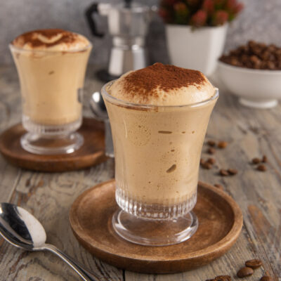 Crema al caffè servita in bicchiere con spessa schiuma e cacao in polvere in superficie