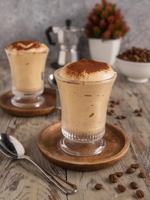 Crema al caffè servita in bicchiere con spessa schiuma e cacao in polvere in superficie