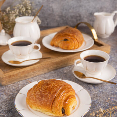 Pain au chocolat dorato e sfogliato servito con caffè nero