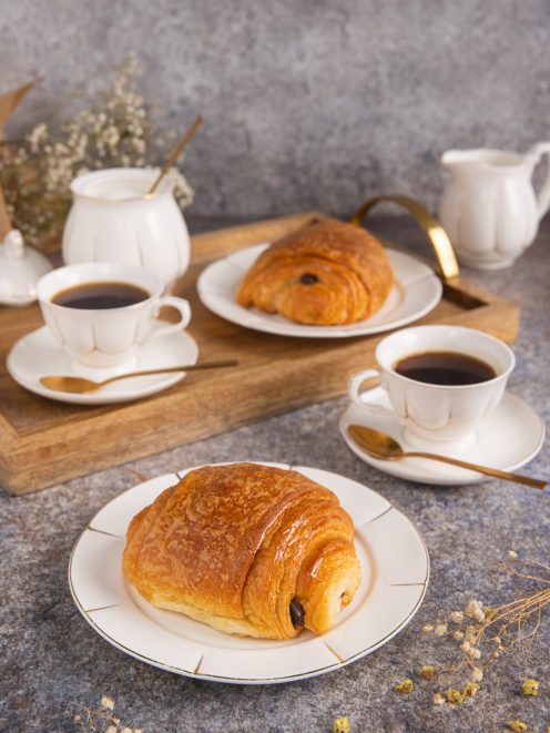 Pain au chocolat dorato e sfogliato servito con caffè nero