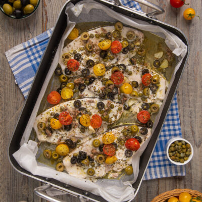 Pesce spada al forno con olive, pomodorini colorati, capperi e acciughe