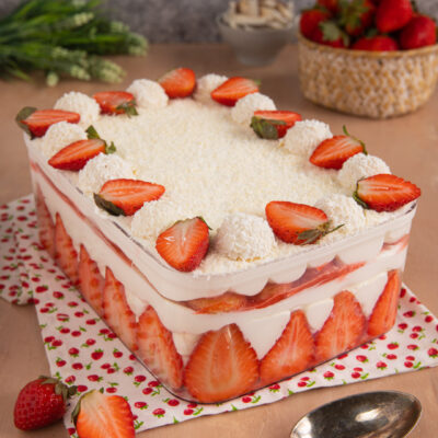 Tiramisù al cocco e fragole a strati con panna, fragole fresche a fette e palline al cocco in superficie
