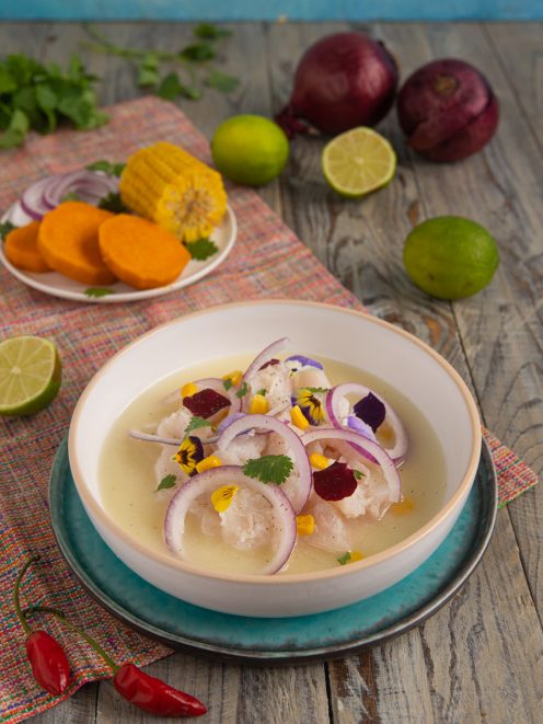 Ceviche con bocconi di pesce bianco, anelli di cipolla rossa, fiori eduli e leche de tigre