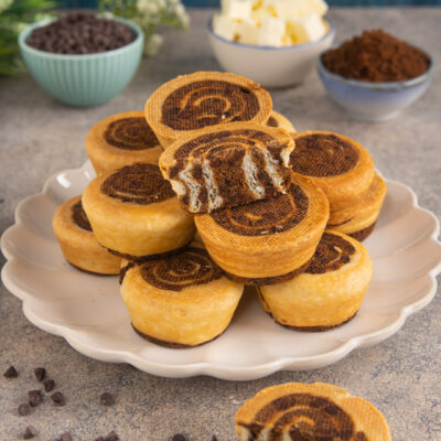 Crookie roll a spirale impilati su piatto con uno tagliato a metà che mostra gli strati al cioccolato