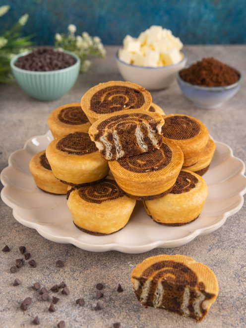 Crookie roll a spirale impilati su piatto con uno tagliato a metà che mostra gli strati al cioccolato