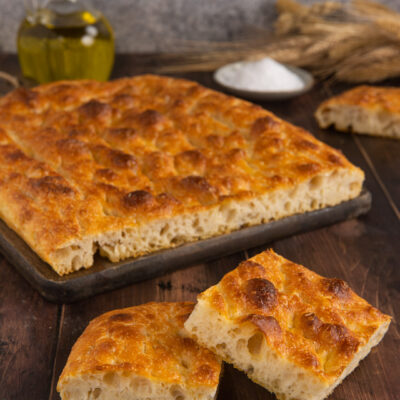 Focaccia senza impasto dorata con crosta alveolata, tagliata a fette pronte da servire