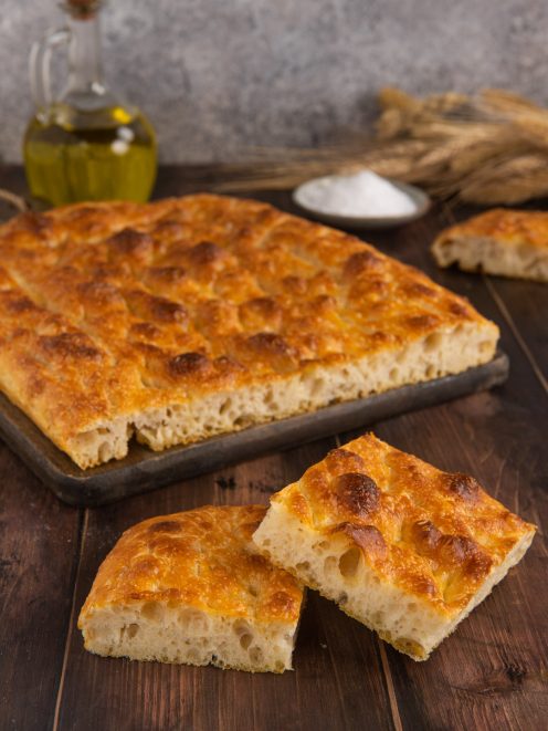 Focaccia senza impasto dorata con crosta alveolata, tagliata a fette pronte da servire