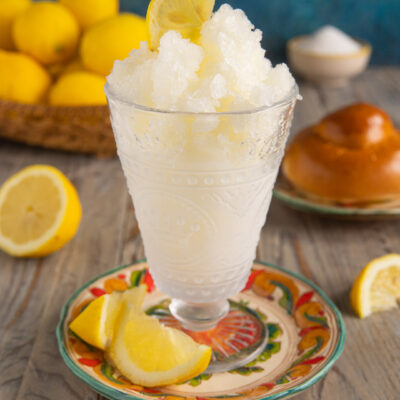 Granita siciliana al limone in coppa di vetro decorata con spicchi di limone freschi