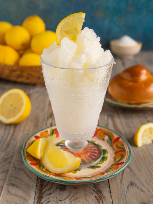 Granita siciliana al limone in coppa di vetro decorata con spicchi di limone freschi