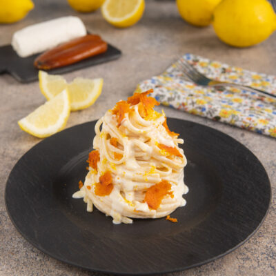 Linguine al caprino con limone e bottarga cremose, guarnite con scorza grattugiata e scaglie croccanti