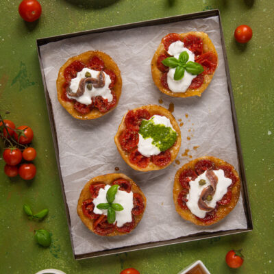 Mini tatin ai pomodorini con burrata, guarnite a scelta con pesto, basilico o acciughe e capperi