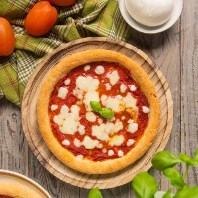 Pizza senza glutine con salsa di pomodoro, mozzarella sciolta e foglie di basilico fresco