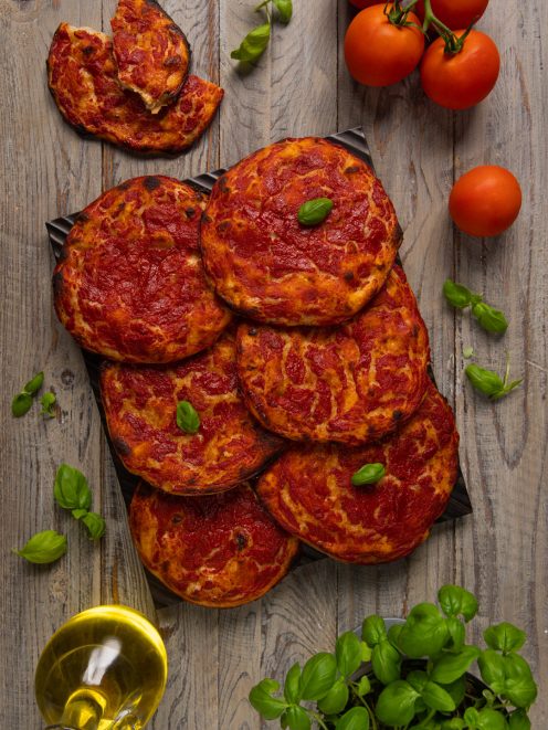Pizzette rosse croccanti con sugo di pomodoro e foglie di basilico fresco