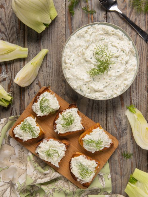 Tzatziki di finocchi in ciotola e spalmato su crostini di pane, guarnito con ciuffi di finocchio
