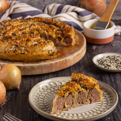 Burek con ripieno di carne macinata avvolto in pasta sfoglia croccante, cosparso di semi di sesamo