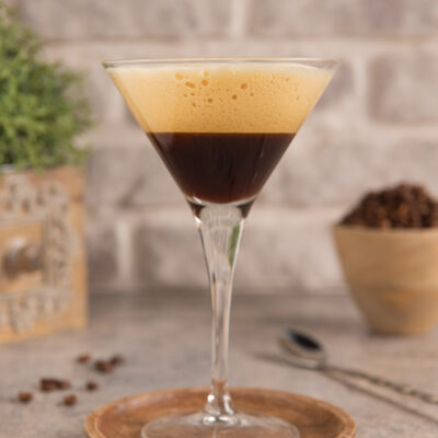 Caffè shakerato servito in coppa martini con schiuma dorata in superficie