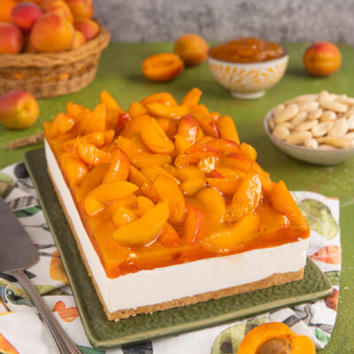 Cheesecake alle albicocche con base di biscotto, crema bianca e spicchi di albicocche caramellate in superficie