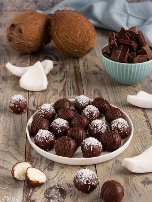 Dolcetti al cocco e cioccolato fondente con scaglie di cocco, uno spaccato mostra il ripieno bianco