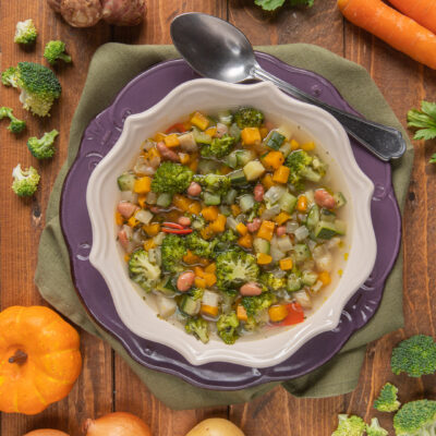 Minestrone di verdure ricco con broccoli, zucca, zucchine, fagioli e sedano in brodo