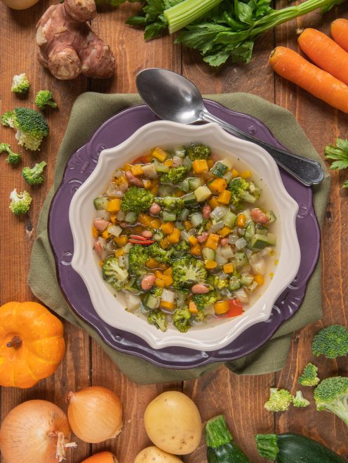 Minestrone di verdure ricco con broccoli, zucca, zucchine, fagioli e sedano in brodo