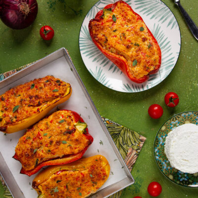 Peperoni ripieni vegetariani gratinati, con ripieno dorato alle erbe, serviti in teglia e su piatto
