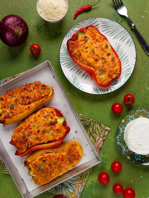 Peperoni ripieni vegetariani gratinati, con ripieno dorato alle erbe, serviti in teglia e su piatto