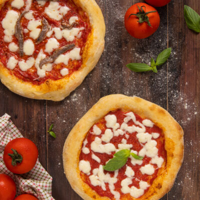 Due pizze napoletane con pomodoro e mozzarella, una con acciughe e una con basilico fresco