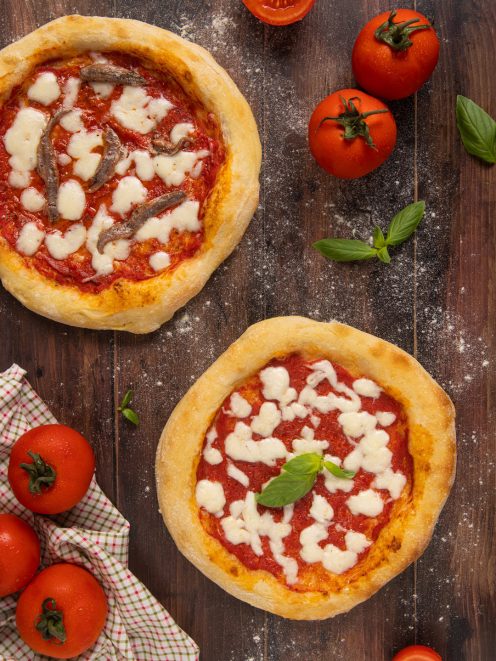 Due pizze napoletane con pomodoro e mozzarella, una con acciughe e una con basilico fresco