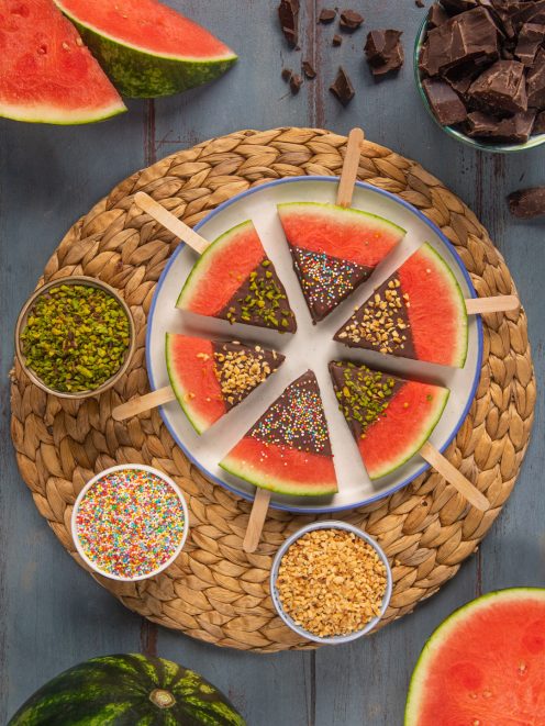 Spicchi di anguria su stecco ricoperti di cioccolato fondente con pistacchi, granella e codette colorate