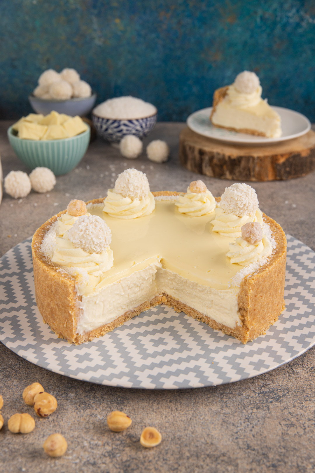 Torta Raffaello tagliata con cuore cremoso, ciuffi di panna, cocco grattugiato e praline bianche