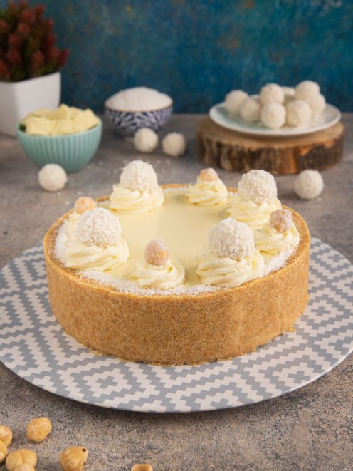 Torta Raffaello con base di frolla, ciuffi di crema al cofano e cocco, decorata con praline e nocciole